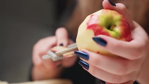 Woman Peeling Fresh Red Apple with Peeler Tool