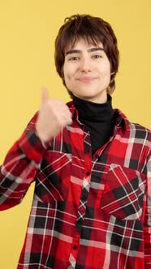 Young Adult Giving Thumbs Up on Yellow Background