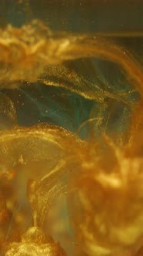 Colorful gold ink and blue dye mixing in liquid