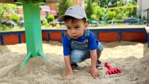 Un adorable bébé caucasien est assis dans un bac à sable.
