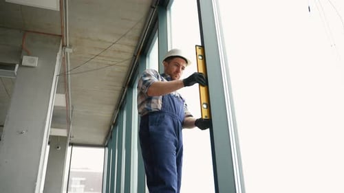 Construction Worker Checking Vertical Alignment of Window Frame