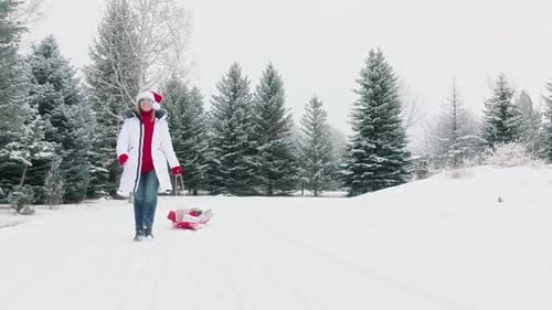 Fond d'hiver cinématographique : Père Noël, femme, tirant des boîtes à cadeaux sur un traîneau rouge