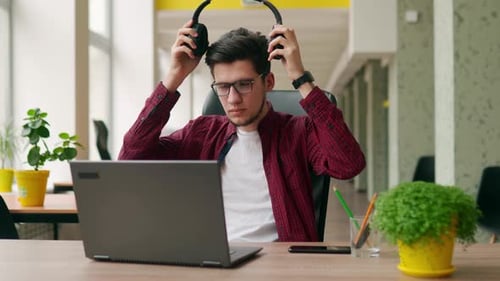 Man Takes Break from Laptop at Office Desk