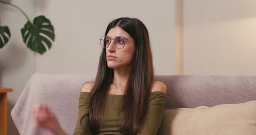Young Woman Sitting Thoughtfully on a Couch Indoors