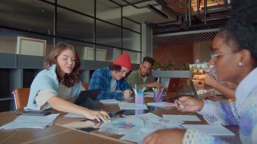 Team of Workers Engages in Workflow at Table in Office