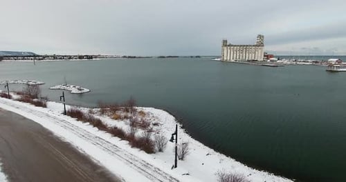 Aerial view flying along the lakeshore of Georgian Bay in Collingwood looking at an industrial build