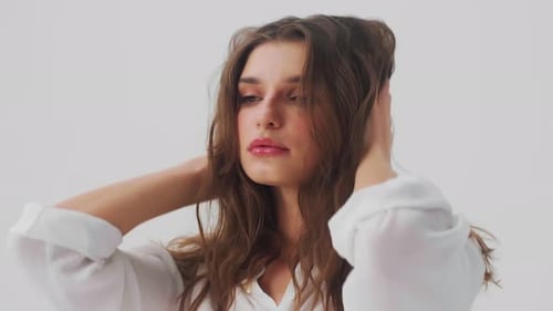Young Fashion Model Posing at Isolated White Background in Studio Playing with Her Hair