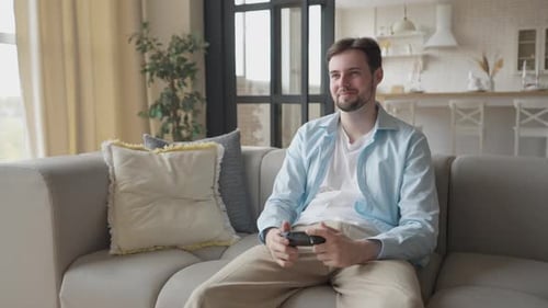 Man Plays Video Game on Couch at Home