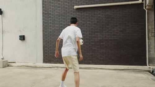 Asian Teenager Man Footballer Performing Tricks with Football Ball Outside