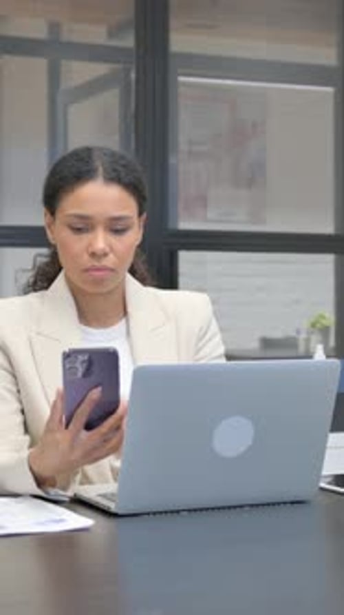 Stylish Woman Working at Desk with Phone and Laptop