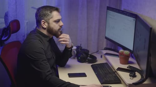 Ein kaukasischer Mann in einem schwarzen Hemd arbeitet von zu Hause aus am Computer
