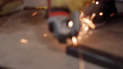 Rack focus of a angle grinder slicing through metal frames, closeup