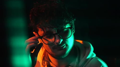 Müder Computerprogrammierer vor einem glitzernden Bildschirm im dunklen Raum, Nahaufnahme