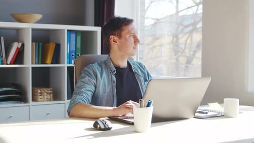Young Male Entrepreneur Works at Home Office at the Computer Workplace of Freelancer or Student