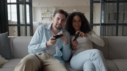 Smiling Couple Playing Video Games on the Couch