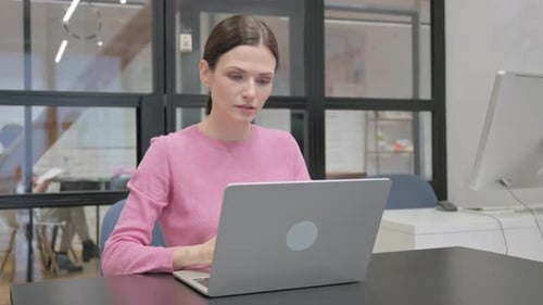 Woman Works on Laptop at Office Desk