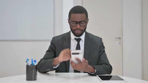 Man Scrolls on Phone at Office Desk