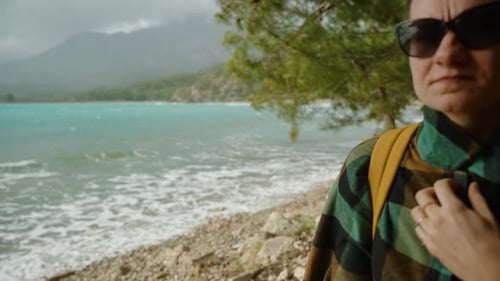 Woman Stands on Rocky Beach Near the Ocean