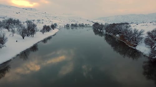 Aerial View river with snow on the trees and the water reflecting the sky