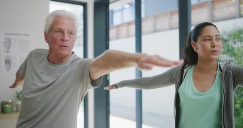 4k video footage of a senior patient practicing yoga with his physiotherapist in her clinic