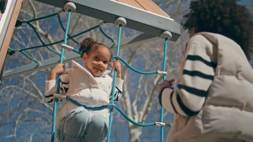 Afrikanisches Kind, das an einer Strickleiter klettert, sonniger Tag, kleines Mädchen spielt auf dem Spielplatz