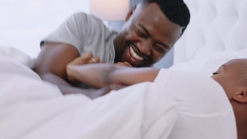 Laughing Couple Embracing in Bed at Home