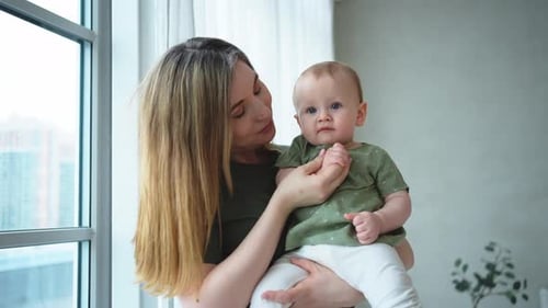 Mother Holding Baby Near a Window