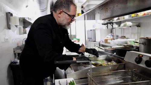 vegetable on the griddle in a modern kitchen while a male cook worker prepares food