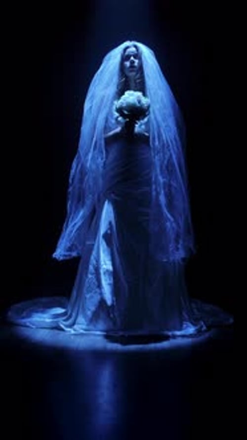 Spooky bride in wedding dress under blue spotlight