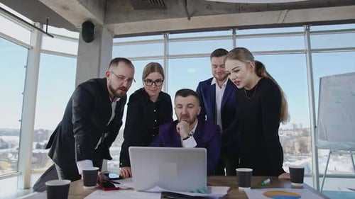 Team Collaborates Around Laptop in Modern Office