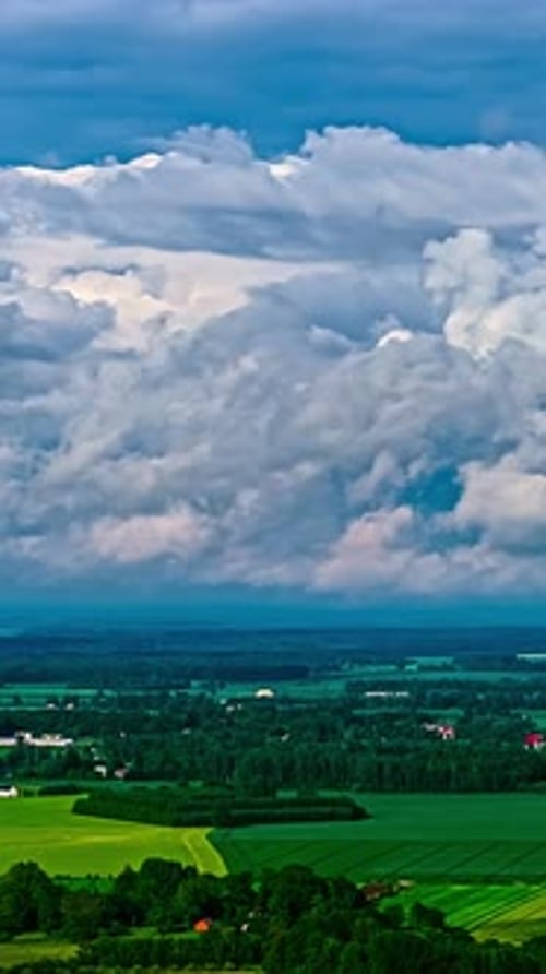 Timelapse of dramatic storm clouds over a vibrant green rural landscape, vertical