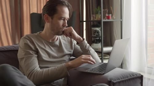 Man Using Laptop on Sofa at Home