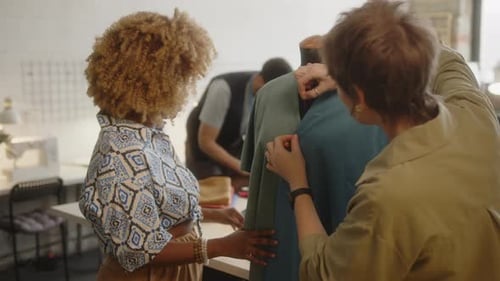 Zwei Näherinnen heften Stoff an eine Schaufensterpuppe im Atelier