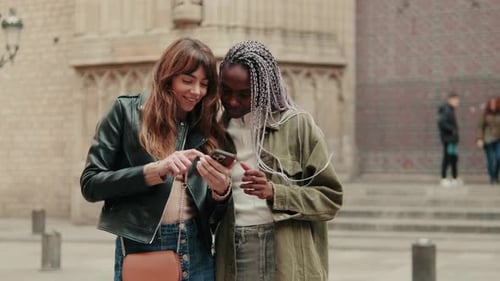 Friends Look at Smartphone Outdoors in City