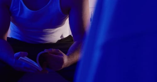 Man in Tank Top Reading Book at Night, Blue Mood Lighting, Close Up Hands