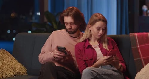 Couple Relaxing on Couch Looking at Smartphones