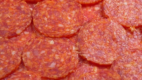 Juicy sliced pepperoni sausage rotating as background for restaurant, food video, food porn. Smoke