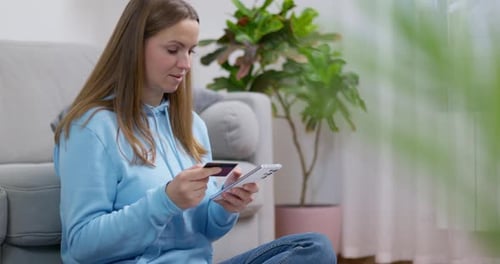 Woman Comparing Credit Card and Smartphone