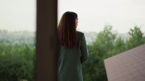 Woman on Balcony Looking Over Rainy City