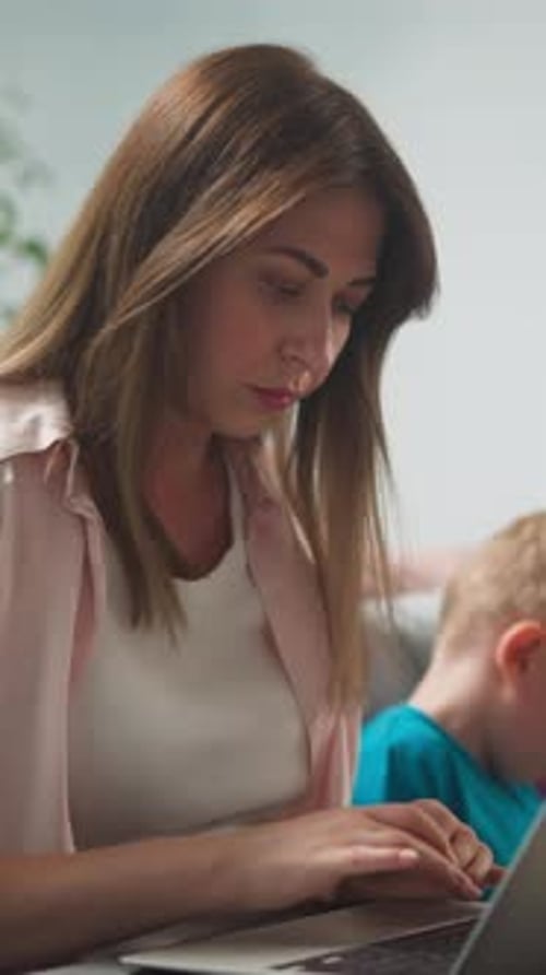Young Woman in Bright Room Works at Home Remotely at Laptop