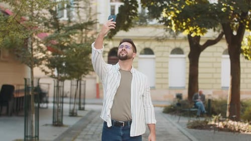 Frustrated Young Man Trying to Catch Signal on Smartphone for Better Connection in City Street