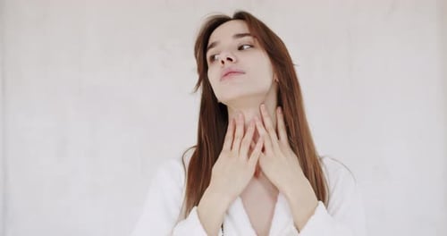 Woman Massaging Face in White Room