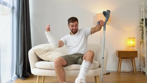 Man Cheering with Leg and Arm Casts Indoors