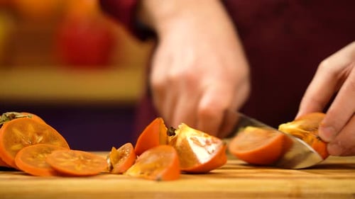 Cutting into pieces of ripe orange persimmon. Man cutting fresh kinglet fruit.