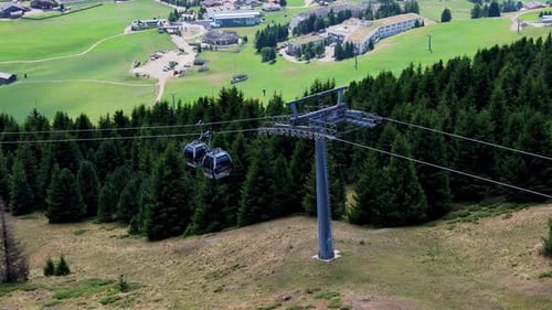 Cable car gliding gracefully over a lush green forest in the mountains