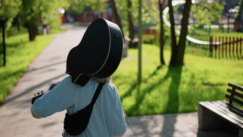 Guitarist Strolling Outdoors Relaxed Guitarist Carrying Case During Sunny City Walk Indie Musician