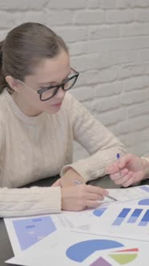 Woman Reviews Charts with Colleague in Office