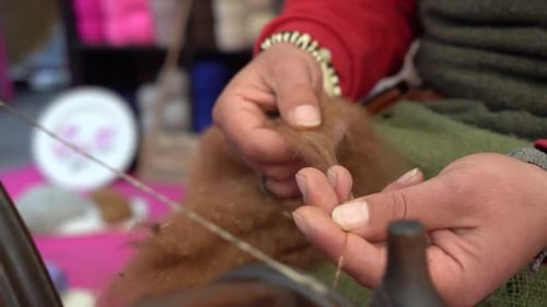 A street artist sewing manufacturing with traditional spinning wheel. Handcraft fiber sew by vintage