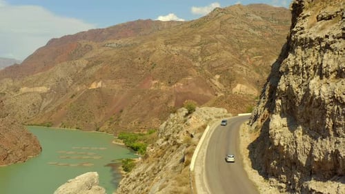 Shooting drone blue mountain river located along busy modern road and sand canyon,