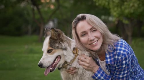 Woman Hugging Her Dog in a Green Field